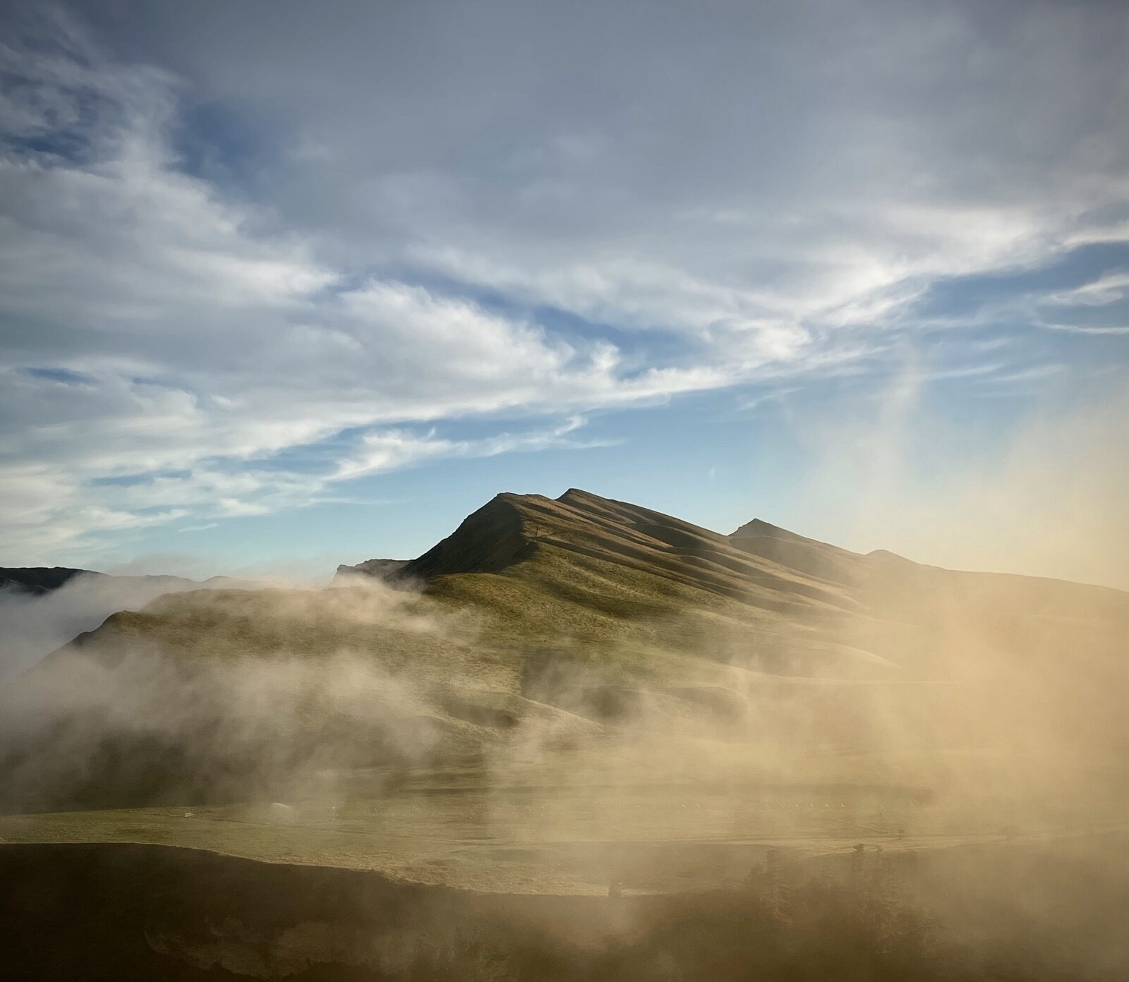 Low cloud rolling across a mountain ridge, obscuring most of the slope.